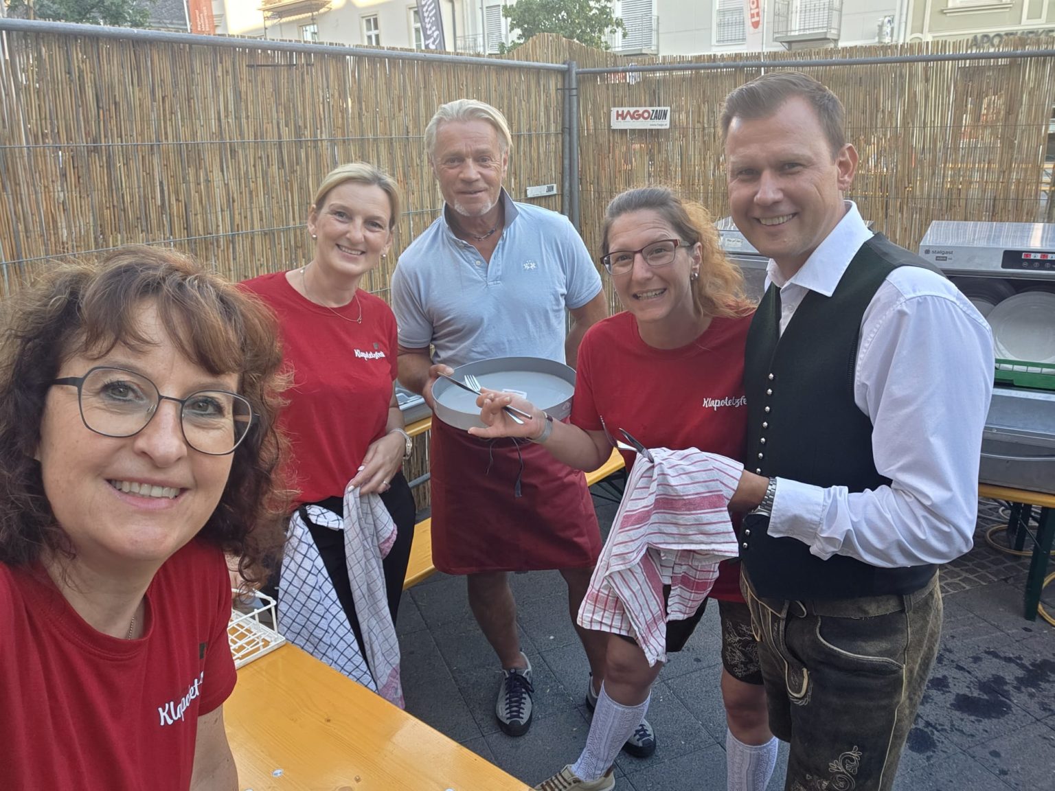 Fünf Personen mit roten T-Shirts und Tracht bei einem Fest in Österreich